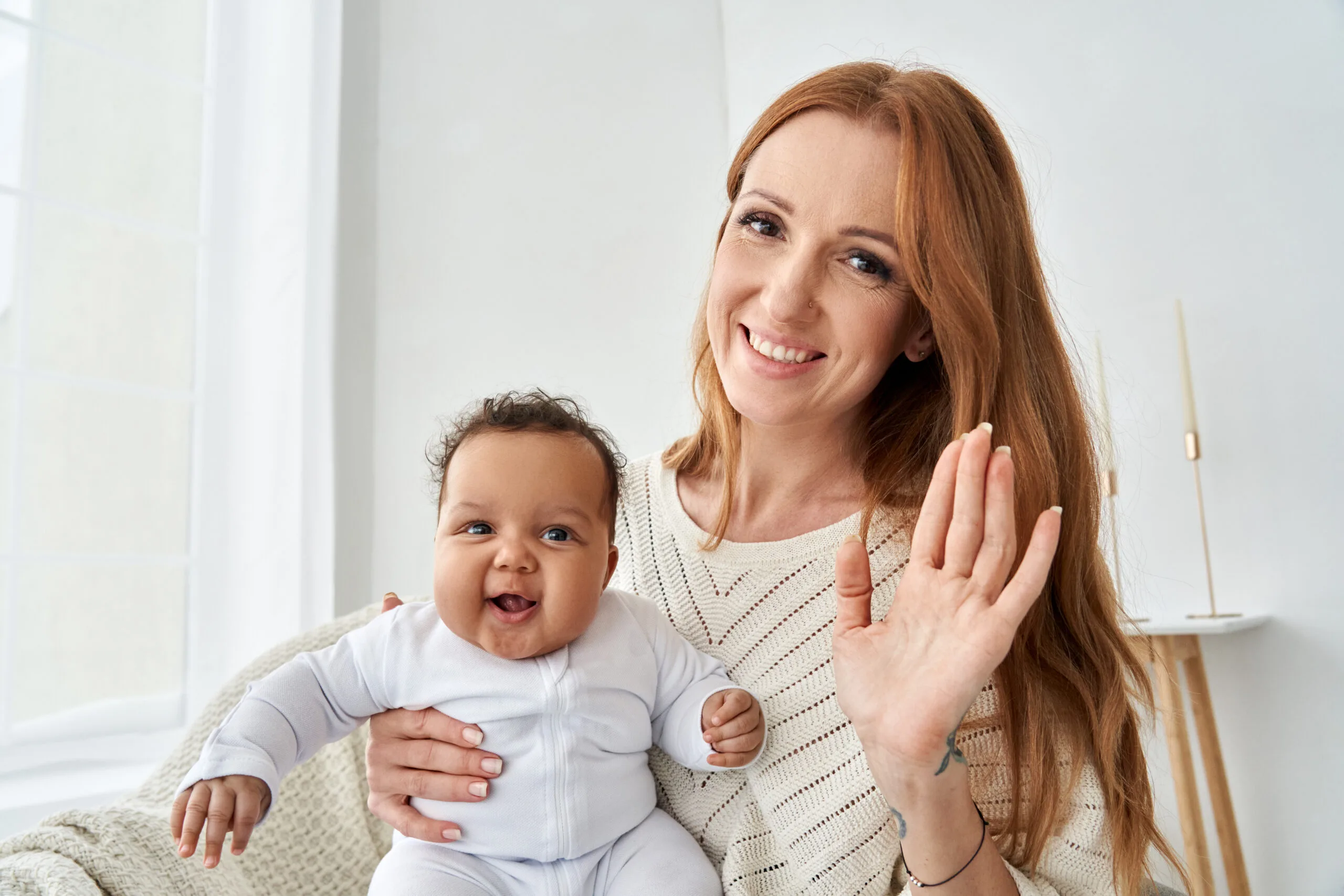 Smiling mother with her happy baby waving at the camera, symbolizing postpartum care, emotional support, and newborn care services in Atlanta